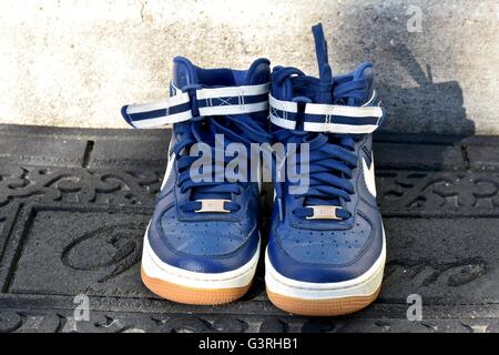 A pair of blue Nike shoes sitting on a door mat in front of a house Stock Photo