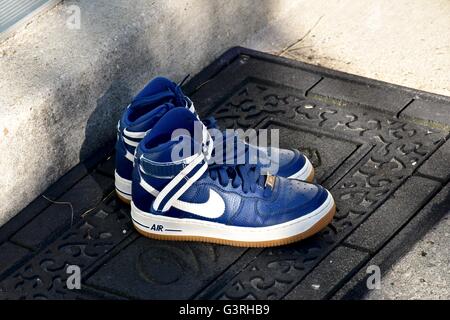 A pair of blue Nike shoes sitting on a door mat in front of a house Stock Photo