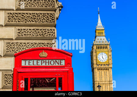 Iconic red telephone box with Big Ben against blue sky in the background Stock Photo