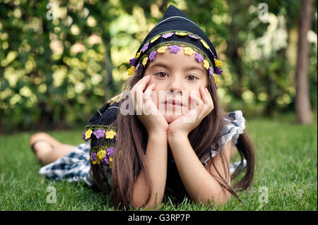 Little girl with headscarf lying on grass Stock Photo