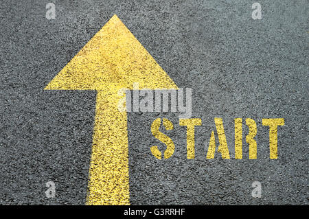 Yellow forward road sign with Start word on the asphalt road. Business concept. Stock Photo