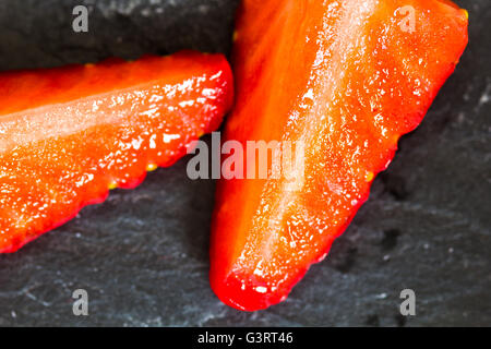 Cut strawberries on slate background Stock Photo