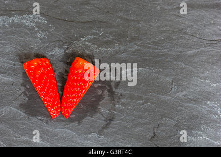 Cut strawberries on slate background Stock Photo