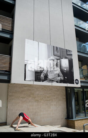 A man does a yoga pose beneath a large photo, part of a local exhibition Stock Photo