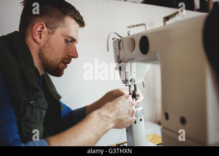 Profile view of cobbler using a sewing machine Stock Photo