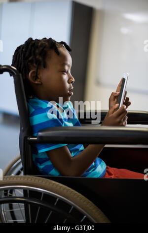 Disabled schoolboy on wheelchair using digital tablet Stock Photo