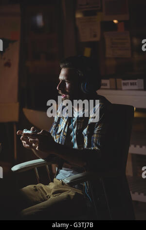 Businessman playing computer games at night Stock Photo