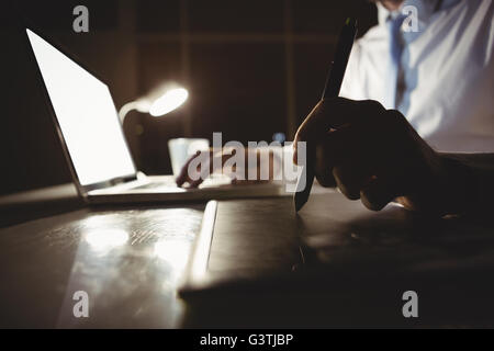 Businessman drawing on graphic tablet at night Stock Photo