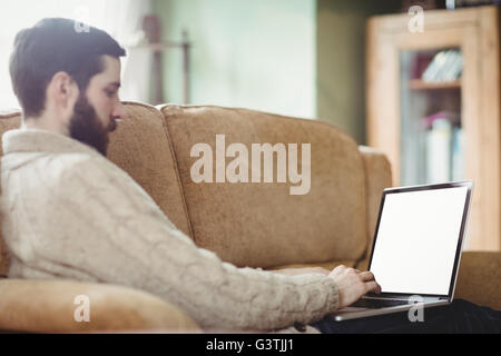 Profile view of hipster man using laptop in sofa Stock Photo