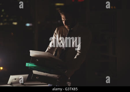 Businessman carrying folder at night Stock Photo