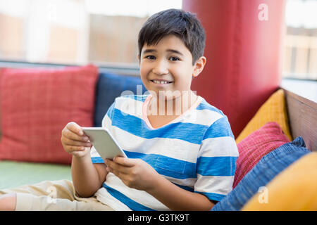 Smiling boy using mobile phone in library Stock Photo