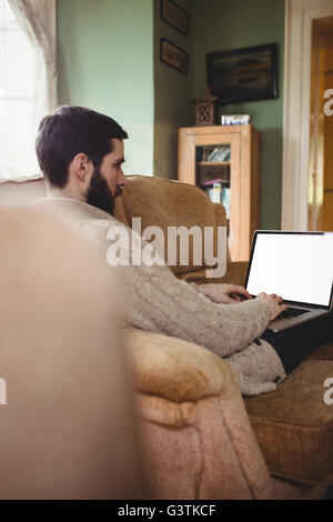 Profile view of hipster man using laptop in sofa Stock Photo