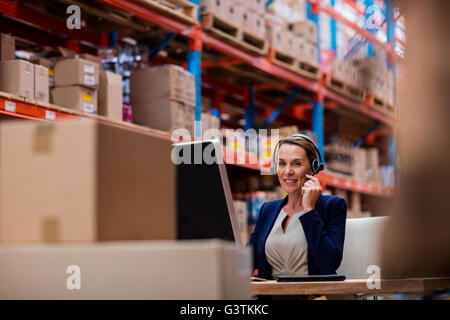 Warehouse manager talking with her headset Stock Photo