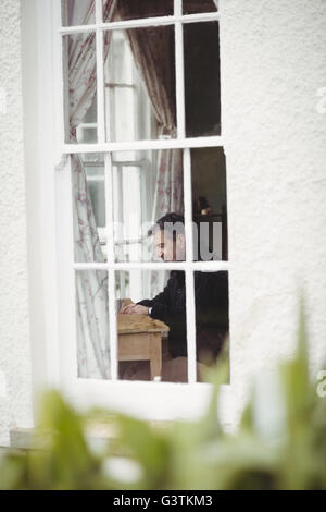 Profile view of man working on laptop at window Stock Photo