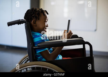 Disabled schoolboy on wheelchair using digital tablet Stock Photo