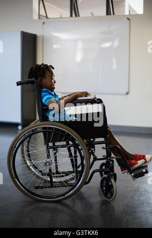Disabled schoolboy on wheelchair using laptop Stock Photo