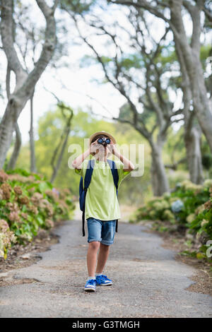 Young boy looking through binoculars in park Stock Photo