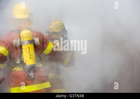 2 firemen in operation surround with smoke Stock Photo