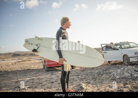 A man preparing to surf at Corralejo in Fuerteventura. Stock Photo