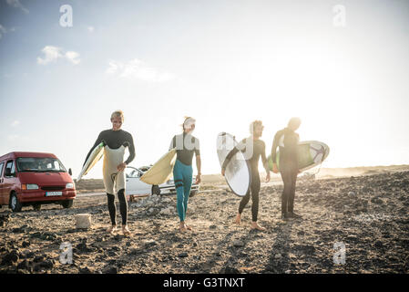 Four men preparing to surf at Corralejo in Fuerteventura. Stock Photo
