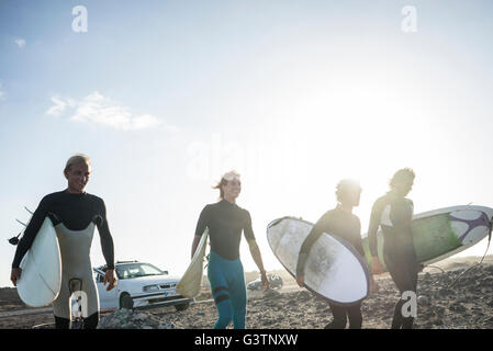 Four men preparing to surf at Corralejo in Fuerteventura. Stock Photo