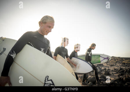 Four men preparing to surf at Corralejo in Fuerteventura. Stock Photo