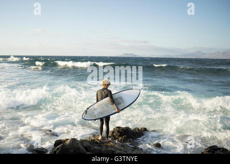A man preparing to surf at Corralejo in Fuerteventura. Stock Photo