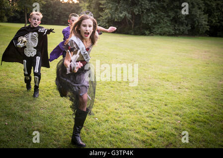 Children chase a girl dressed as a zombie prom queen for Halloween Night. Stock Photo