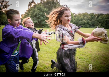 Children chase a girl dressed as a zombie prom queen for Halloween Night. Stock Photo