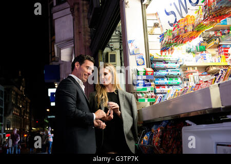 A smartly dressed couple buying confectionary from a kiosk on Oxford Street in London. Stock Photo