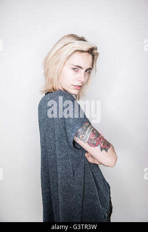 A young tattooed woman posing in a studio looking cool. Stock Photo