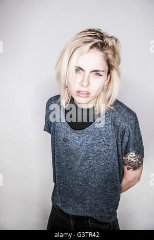 A young tattooed woman posing in a studio looking angry. Stock Photo