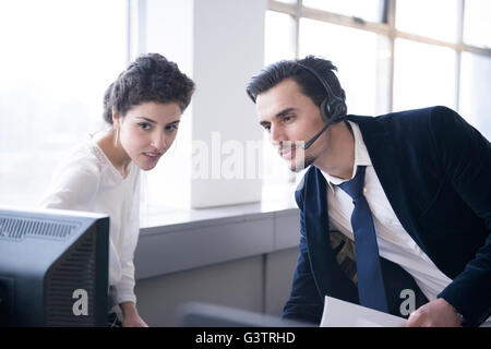 Two colleagues analysing business data on a computer in an office environment. Stock Photo