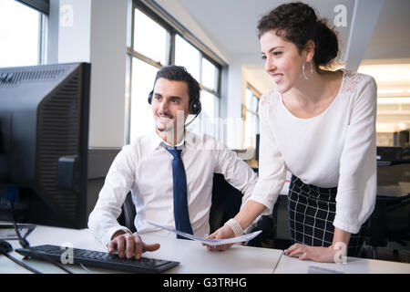 Two colleagues analysing business data on a computer in an office environment. Stock Photo