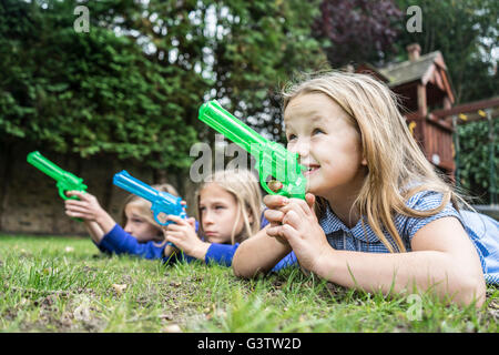 Three ten year old girls in school uniform holding water pistols. Stock Photo