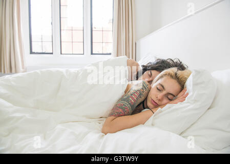 A cool young tattooed couple sleeping in a bed. Stock Photo