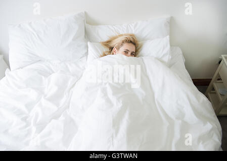 Baby girl pulling up pants on bed stock photo