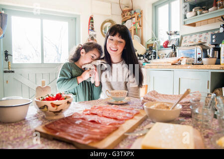 A six year old girl being comforted by her mother at the dinner table. Stock Photo