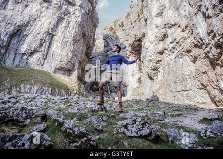 A man standing with arms aloft in rugged terrain. Stock Photo
