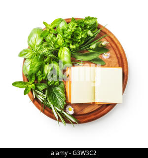 Herbs on cutting board. Fresh basil, parsley, sage, peppermint, rosemary bunch and recipe book. Single object isolated on white Stock Photo