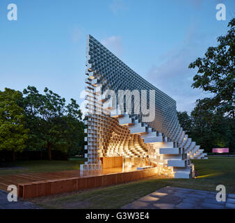 Oblique view of illuminated entrance to pavilion. Serpentine Pavilion 2016, London, United Kingdom. Architect: BIG Bjarke Ingels Group, 2016. Stock Photo