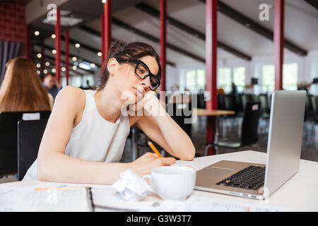 Pretty bored young businesswoman working using laptop in office Stock Photo