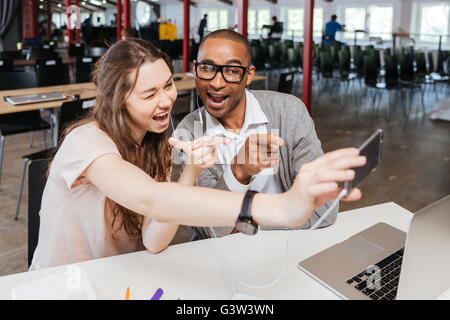 Cheerful funny young business people working and taking selfie in office Stock Photo
