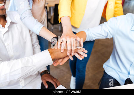 Closeup of multiethnic group of young people standing and joining hands Stock Photo