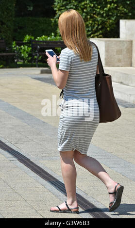 Young woman walks on the street with a smartphone Stock Photo