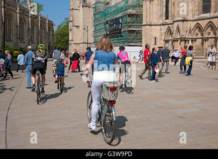 People woman cycling past tourists in town city centre near the Minster in summer York North Yorkshire England UK United Kingdom Great Britain Stock Photo