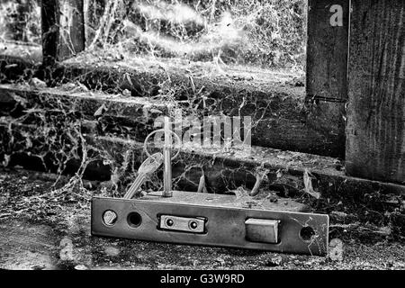 Door locking mechanism with keys on a window ledge covered in cobwebs Stock Photo