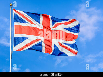 Union Jack flag of United Kingdom of Great Britain and Northern Ireland, flying on a pole against blue sky. Stock Photo