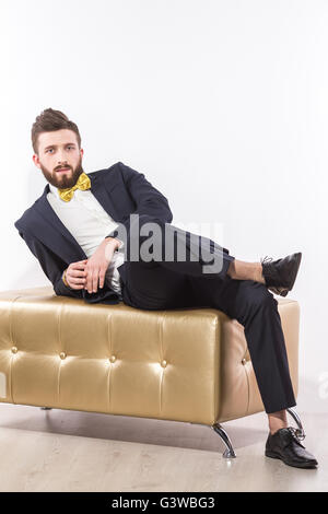 Elegant young handsome man in black classic suit with yellow bow-tie Stock Photo