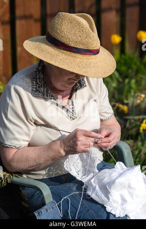 Mature woman. knitting baby shawl for grandchild.Arts and crafts. textiles.UK staying home Stock Photo